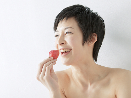 笑顔でイチゴを食べる女性